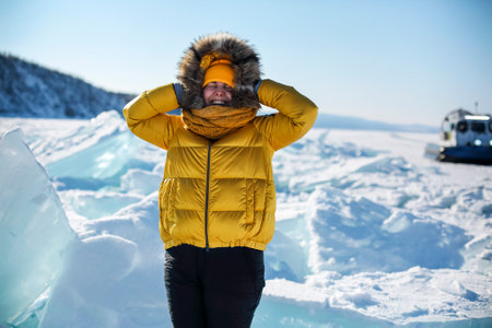 Portrait of happy real pretty woman in fur coat and yellow hat at winter background. Baikal lake. Winter travel and adventure conceptの写真素材