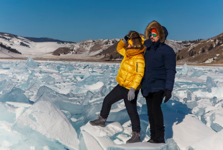 Happy couple on the frozen winter Lake Baikal. transparent ice. Travel in winter, active recreation, sports, holiday.の写真素材