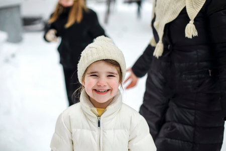 Joyful family grandmother with grandchildren in warm clothes playing outdoors in winter park,...