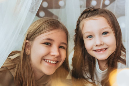 Cozy domestic portrait of two happy smiling little girls sisters hugging embracing while spending...
