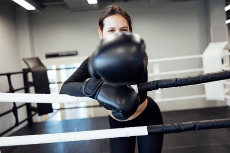 Strong latin boxing woman on the ring at fitness gym. Athletic girl training Muay Thai boxing for bodybuilding and healthy lifestyle concept. Workout in sports clubの写真素材