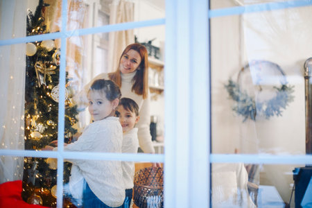 Cute little children helping parents to decorate Xmas tree at home, happy parents and small kids preparing for Christmas and New Year, decorating house for upcoming winter holidays, selective focusの写真素材