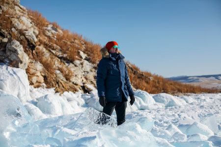 Travel and winter holiday. Lake Baikal. Portrait of the man tourist in red cap and blue jacket...