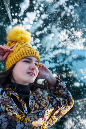 Fashionable image of a stunning woman posing on Baikal Lake ice wearing yellow hat. Boho dress flies in the wind. Beautiful ice landscapes of Lake Baikalの写真素材