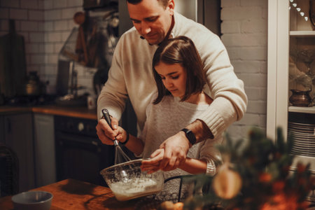 Young family, parent and child cooking homemade cake together in cozy kitchen at home during winter holidays, father helping daughter to prepare dough for pie. Cooking with kidsの写真素材