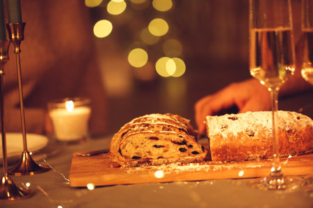 Selective focus of female cutting delicious freshly baked homemade xms pie with knife, celebrating Christmas Eve or New Year with friends or family at home decorated with led lights, defocused. Stollenの写真素材