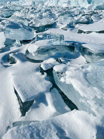 Pieces of ice lying on the ideal smooth ice of baikal with ice hummocks in the horizon. Sun is shining through the sides of ice cubes. Floes look like diamondsの写真素材