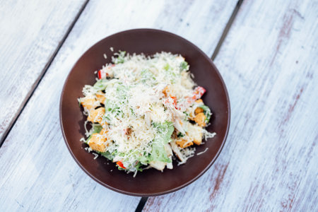 Top view Classical Caesar salad with roasted chiken, quail eggs, lettuce leaves, becon, parmesan slices and cherry tomatoes on the white plate on the white tableの写真素材