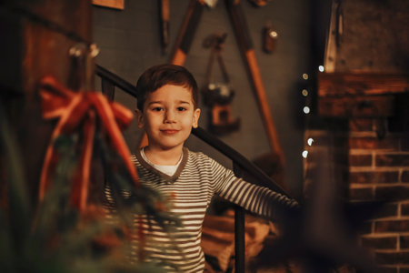 Portrait of cute little boy smiling at camera while standing indoor of big cozy rustic farmhouse...