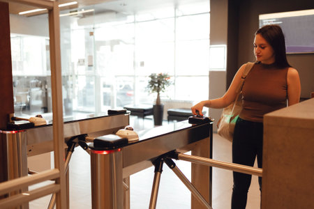 Young brunette woman in sportswear checking the sport bracelet while standing in front of window at gym at reception areaの写真素材