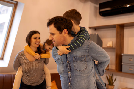 Happy parents with son and daughter posing indoors. Beautiful family looking to the camera in modern...