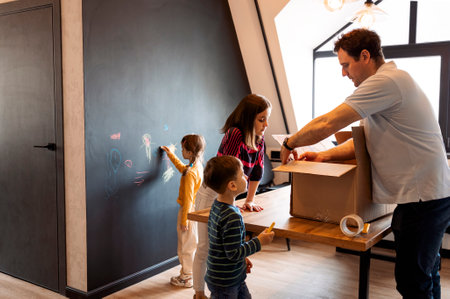 Happy family playing into new home. Child having fun together with father. Sister and brother help....