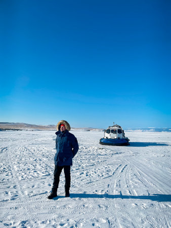 Portrait of the man wearing winter clothes standing by Khivus. Transport on ice. On the surface of the transparent frozen Lake Baikal. Russia. Travel and winter holiday conceptの写真素材