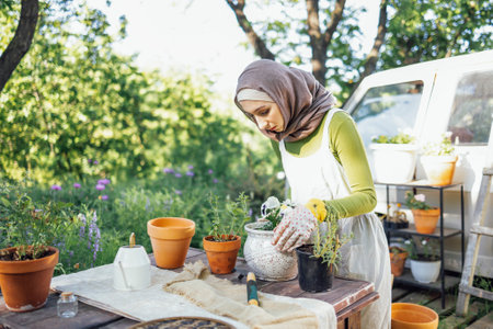 Muslim young attractive gardener at work, take care of green plants, working in retro garden shopの写真素材