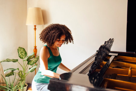 Young black lady playing a piano. Happy smiling woman enjoy fun learning to play piano music instrument.の写真素材