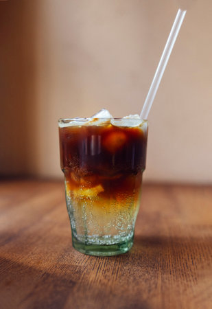 Iced coffee with orange. Glass of americano mixed with craft soda and yuzu orange juice on blurred...