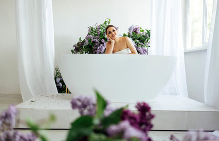 Woman folding arms on a hot tub and placing her chin on them while sitting with smile, flowers on...