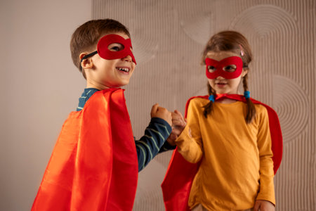 Portrait of a team of two young superheroes, brother and sister, over beige background. superhero child. Super hero kid playing at home. Idea, freedom, friendship, happy childhood conceptの写真素材