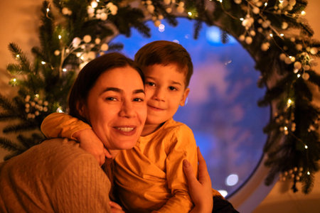 Christmas miracle. Portrait of family mother with little son looking out window on Christmas Eve at...