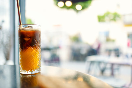 Iced coffee with orange. Glass of americano mixed with craft soda and yuzu orange juice on blurred background, Refreshing summer drink concept.の写真素材