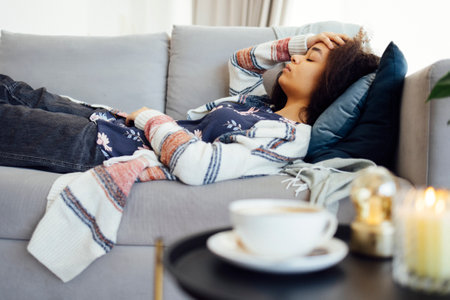 Young unhappy mixed race woman holding her head and suffering from stomach pain and a headache on...