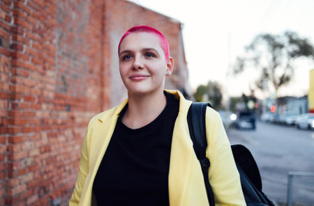 Young redhaired bald woman on the street. Girl with short shaved hair walking in the evening in the...