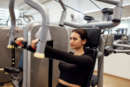 Attractive brunette sportive woman doing exercises on the simulator in fitness club. Sport,...