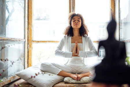 Young adult happy fit slim healthy African American ethnic woman wearing white clothes sitting in...