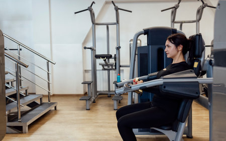 Attractive brunette sportive woman doing exercises on the simulator in fitness club. Sport,...