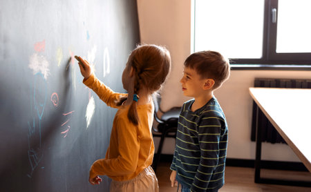 Cute little girl and boy drawing with crayon color on the wall. Works of child. Cute siblings...
