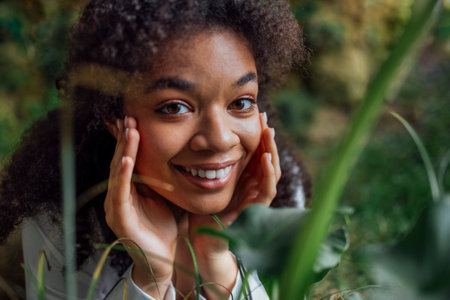 Close up portrait of pretty young african american woman lying on grass. Beautiful afro girl in a...