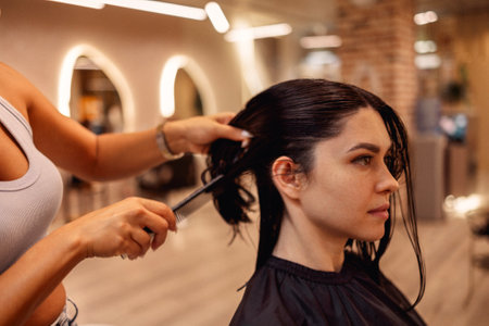 Professional female hairdresser cuts hair of woman while working in beauty salon