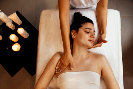 Close up portrait of a young beautiful woman getting facial massage. The brunette female enjoys this procedure. spa treatments. Yourself and skincare concept. copy spaceの写真素材