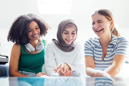 Close up portraits of three smiling teenage girls. Muslim in a hijab, african american and white females teens. Young and positive girls indoor. friendship concept.の写真素材