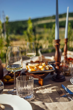 Wedding. Banquet. Chairs and a table for guests, decorated with candles, are served with cutlery and crockery and covered with beige tablecloth. The table stands on a green summer backyard banquet areaの写真素材