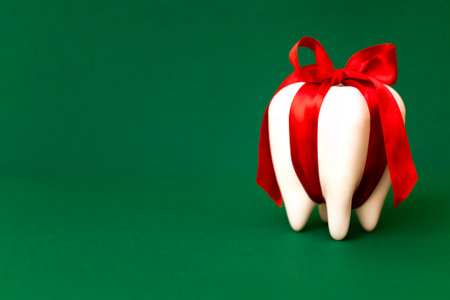 Tooth as a gift. Large white modal molar is tied with a red ribbon with a bow. Bright green...
