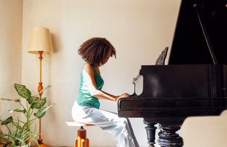 Young black lady playing a piano. Happy smiling woman enjoy fun learning to play piano music instrument.の写真素材