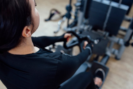Attractive brunette sportive woman doing exercises on the simulator in fitness club. Sport, healthcare, fitness conceptの写真素材