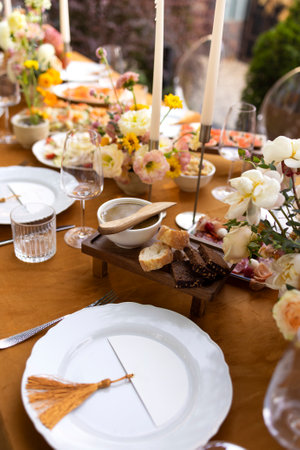 Wedding. Banquet. Chairs and a table for guests, decorated with candles, are served with cutlery and crockery and covered with yellow tablecloth. The table stands on a green lawn in the backyard banquet areaの写真素材