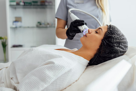 Microneedle RF lifting procedure. hardware cosmetology. Beautician conducts a facial rejuvenation procedure for a brunette womanの写真素材
