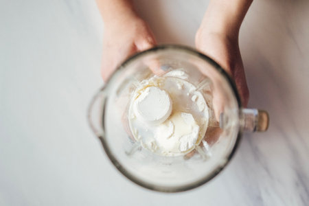 Female hands hold glass jar of stationary blender with white powder for making healthy cocktail. Process of making protein shake. light background. fitness drinks. top view. copyspace.の写真素材