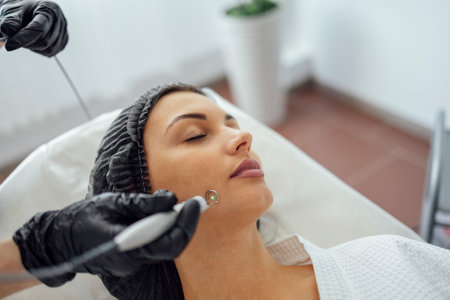 Beautiful caucasian young woman is doing a mole removal procedure in a modern beauty cosmetic dermatological clinic. Skin moles treatment by laser method. close up. Free space for textの写真素材