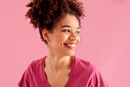Attractive smiling female african american with sincere beautiful smile on pink background. Close up of curly haired black young girl having fun in pink studio. isolated background. copy spaceの写真素材