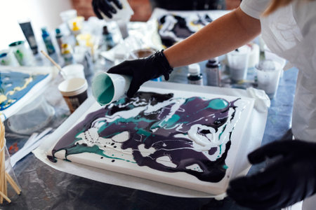 Master class on an Acrylic Fluid Pouring. Teacher and teen girl paint with liquid acrylic in an art...