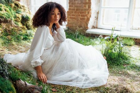 Fashion and beauty shooting a charming mixed race girl in a long white dress. Beautiful girl on the...