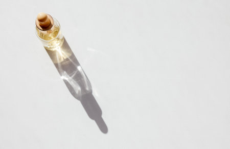 Serum with collagen and peptides in transparent glass bottle on light background with sunlight shadow. Skincare essence for beautiful healthy skin. top viewの写真素材