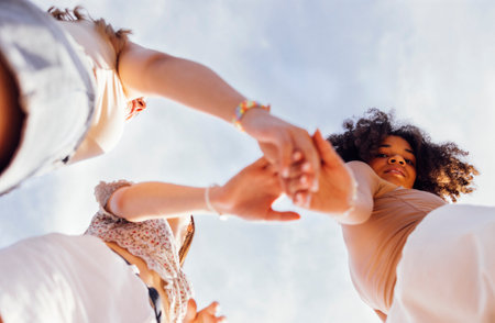 Hands of multiracial smiling teenager gilrs standing and looking to each other. Group of happy cheerful female friends in casual clothes having fun together outdoors. low angle view. copyspace.の写真素材