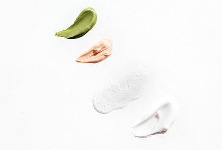 Cosmetic smears of green, pink and white colors cream on bright background. Various textured smear...
