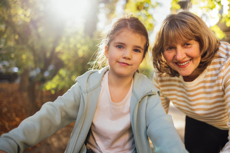 Little girl hugging smiling middle aged woman. Cute female kid and her grandmother enjoy walking...