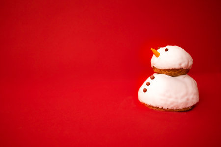 A little cute snowman made of cookies and white cream with chocolate buttons and eyes. Bright red background. Minimalism. Christmas holiday celebrate concept. Happy New Year eve atmosphere. Copy spaceの写真素材